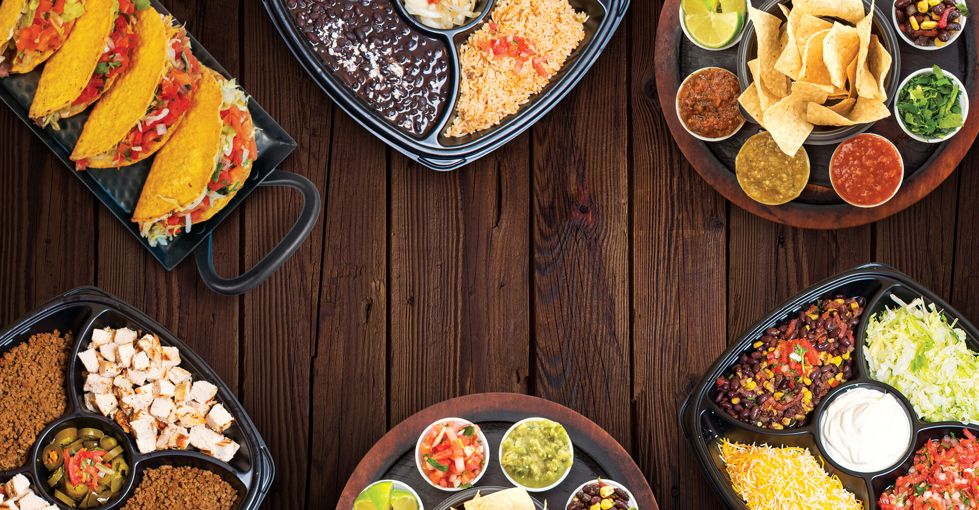 Catered Mexican food meal on a table with tacos, rice, beans, and salsas