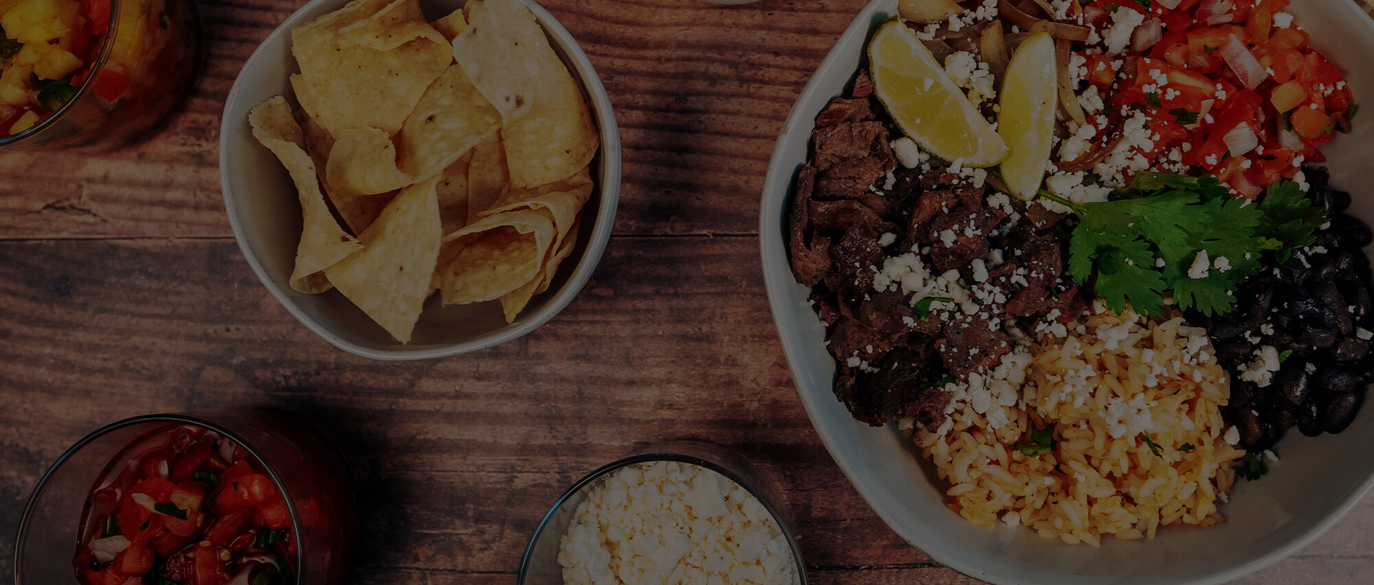 LIME Fresh Mexican Grill chips, burrito bowl and sides on a table