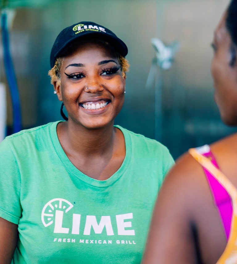 A LIME Fresh Mexican Girl employee smiles at a customer