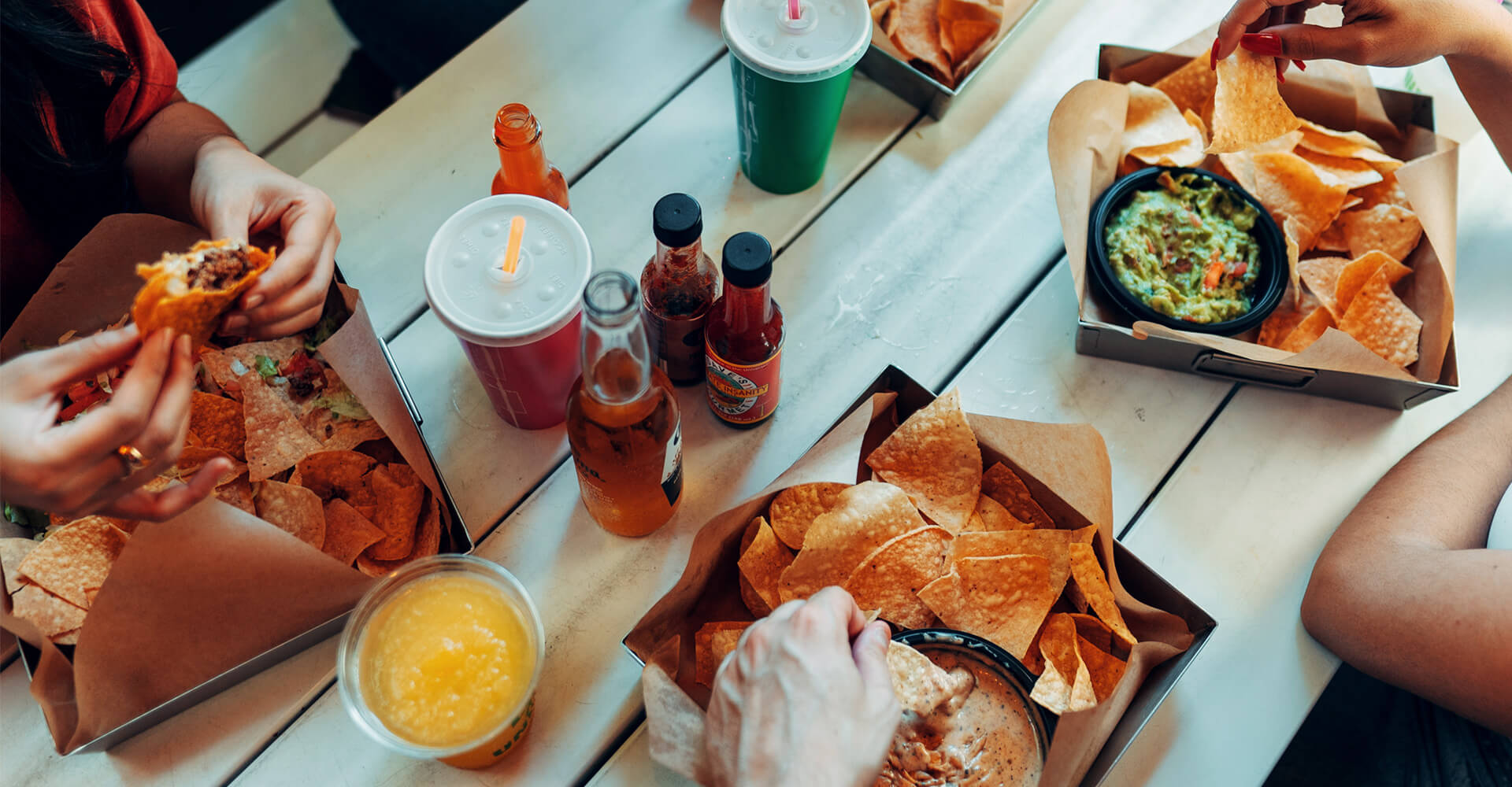 Friends sit at a table and eat Mexican food takeout