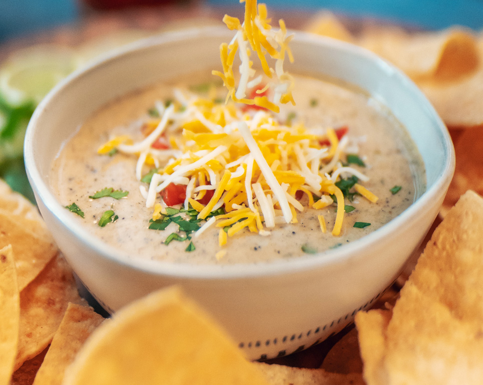 homemade queso dip topped with shredded cheese